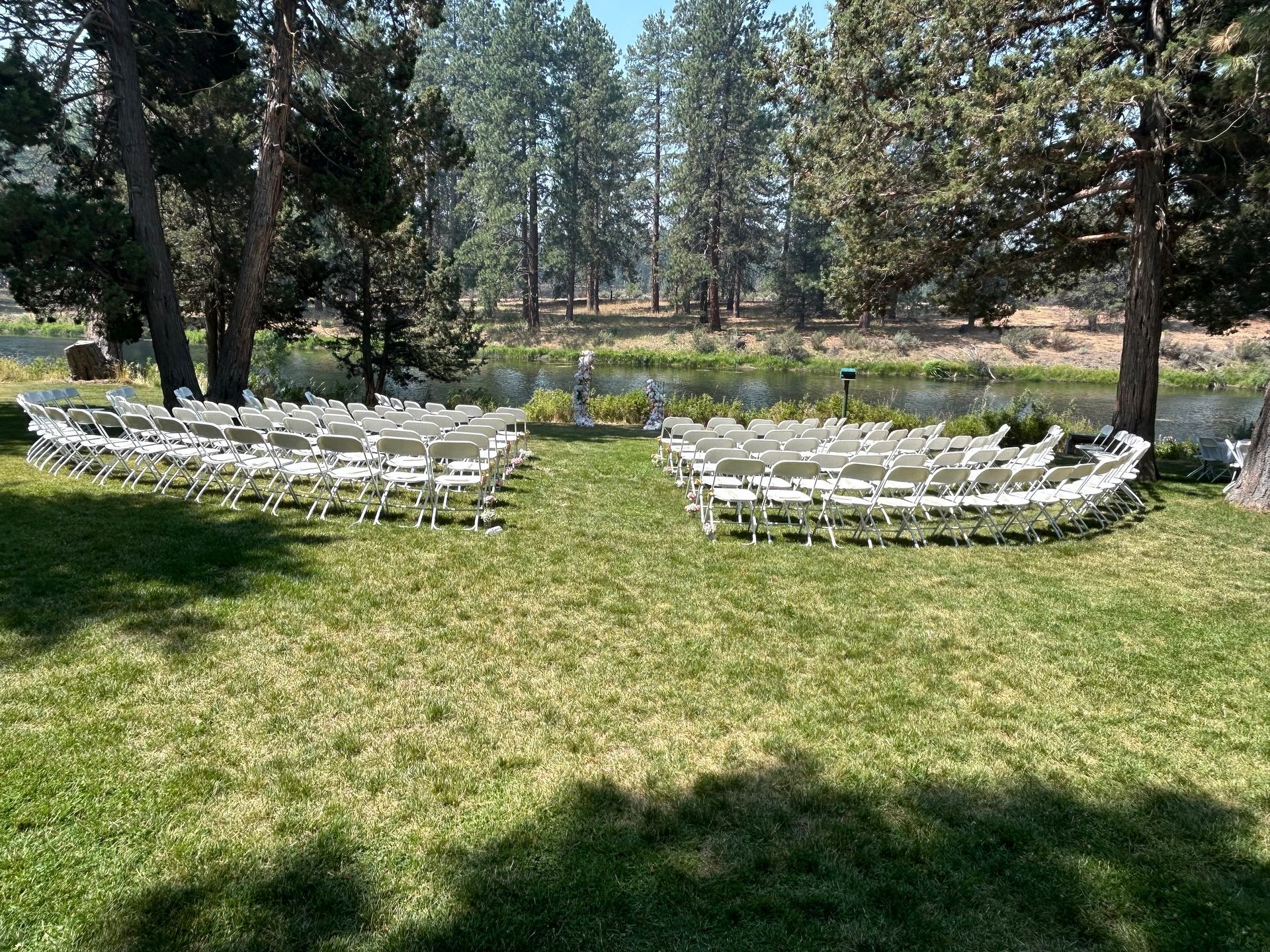 A row of white chairs are lined up in a grassy field.