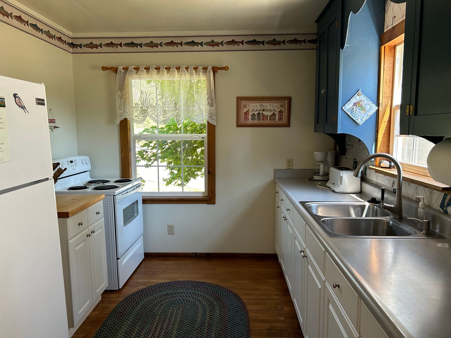 A kitchen with a stove , sink , refrigerator and window