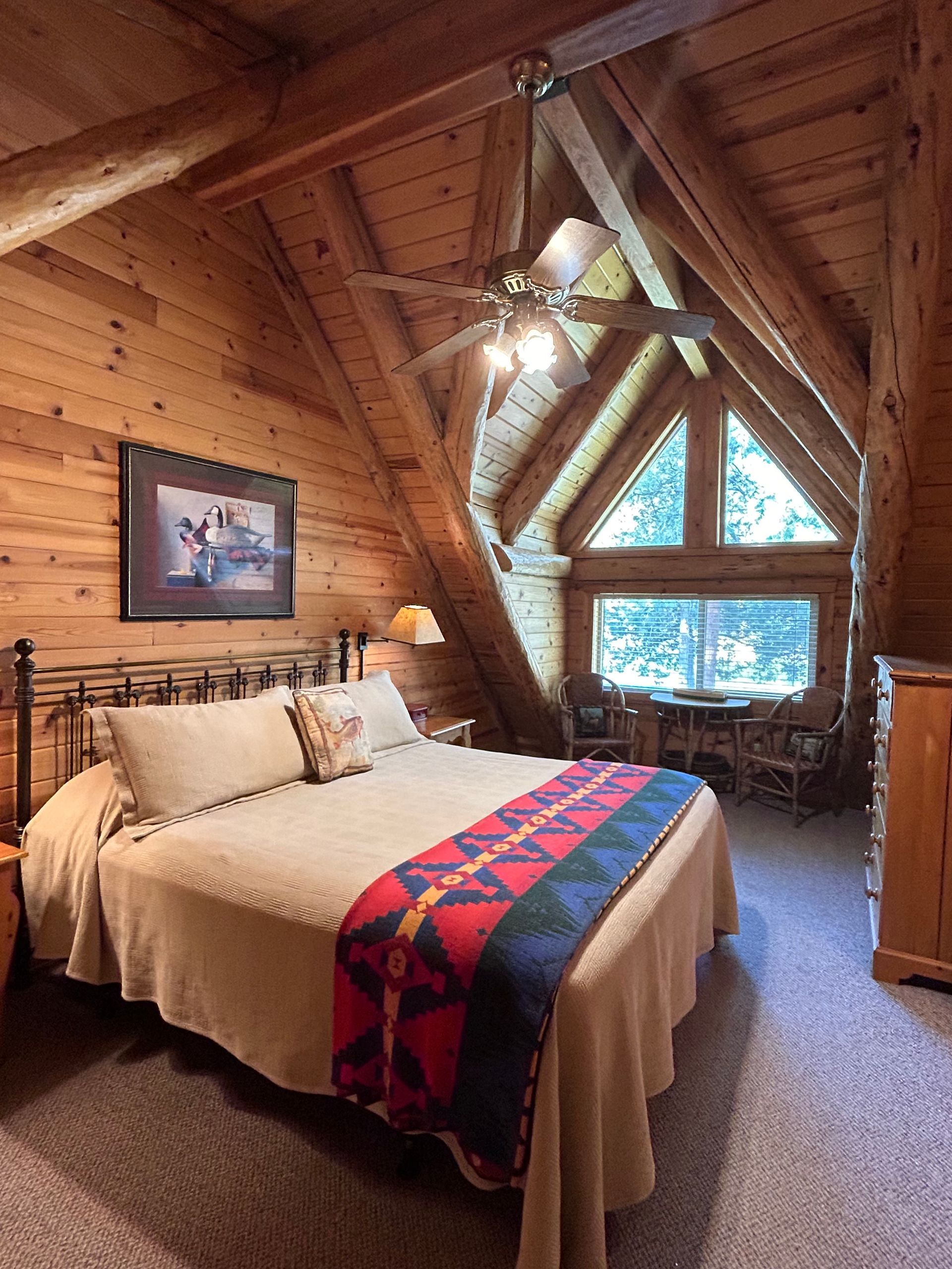 A bedroom in a log cabin with a king size bed and a ceiling fan