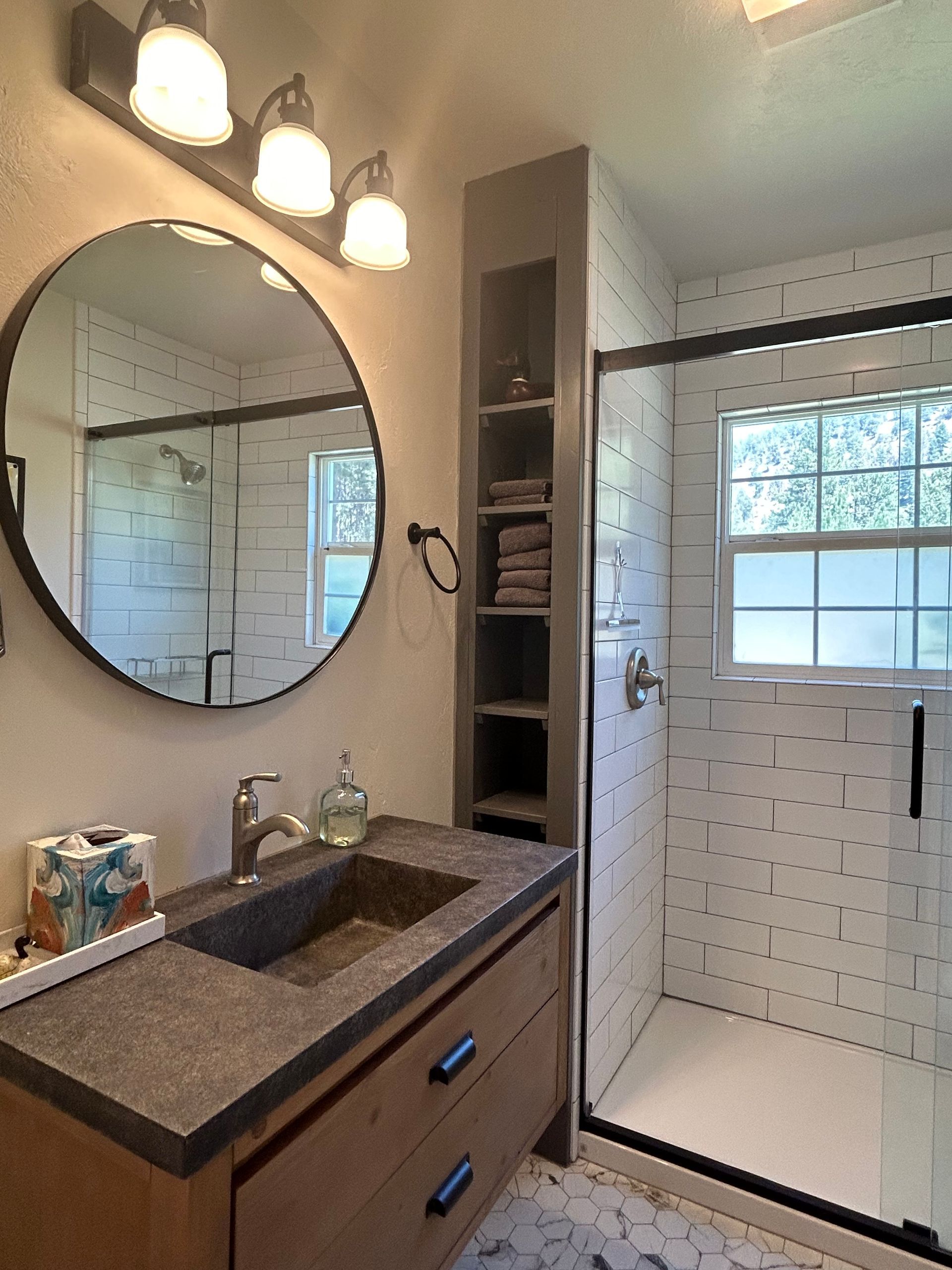 A bathroom with a sink and a round mirror