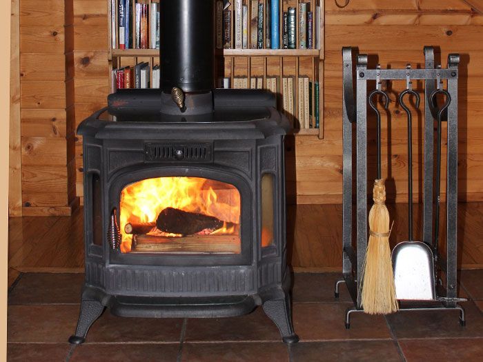 A wood stove is lit up in a wooden room