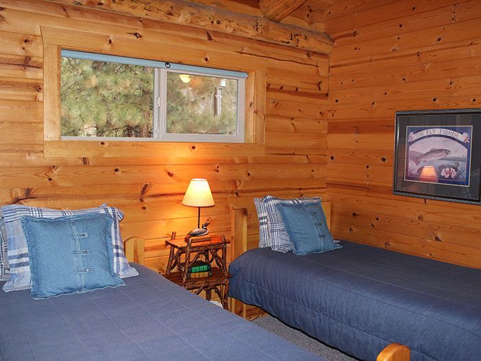 A bedroom in a log cabin with two twin beds