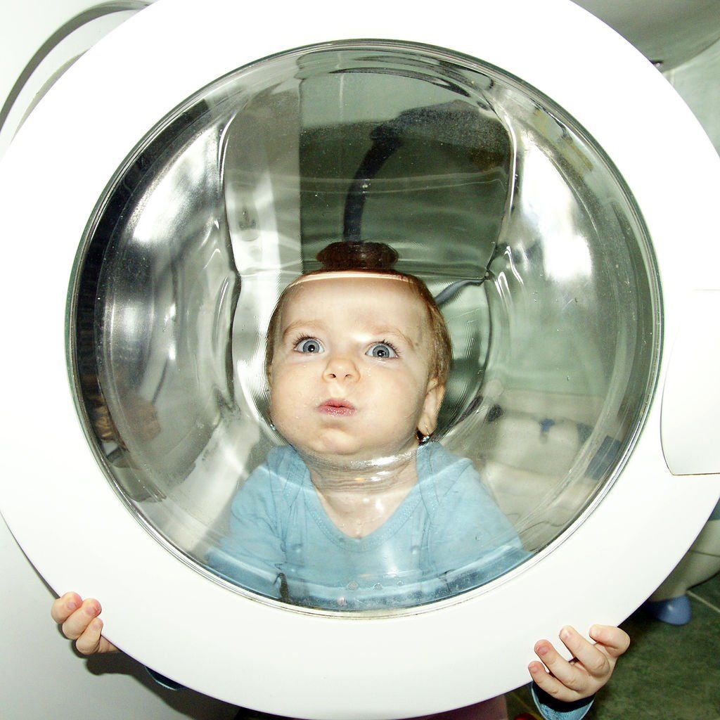 Baby looking through a washing machine door glass