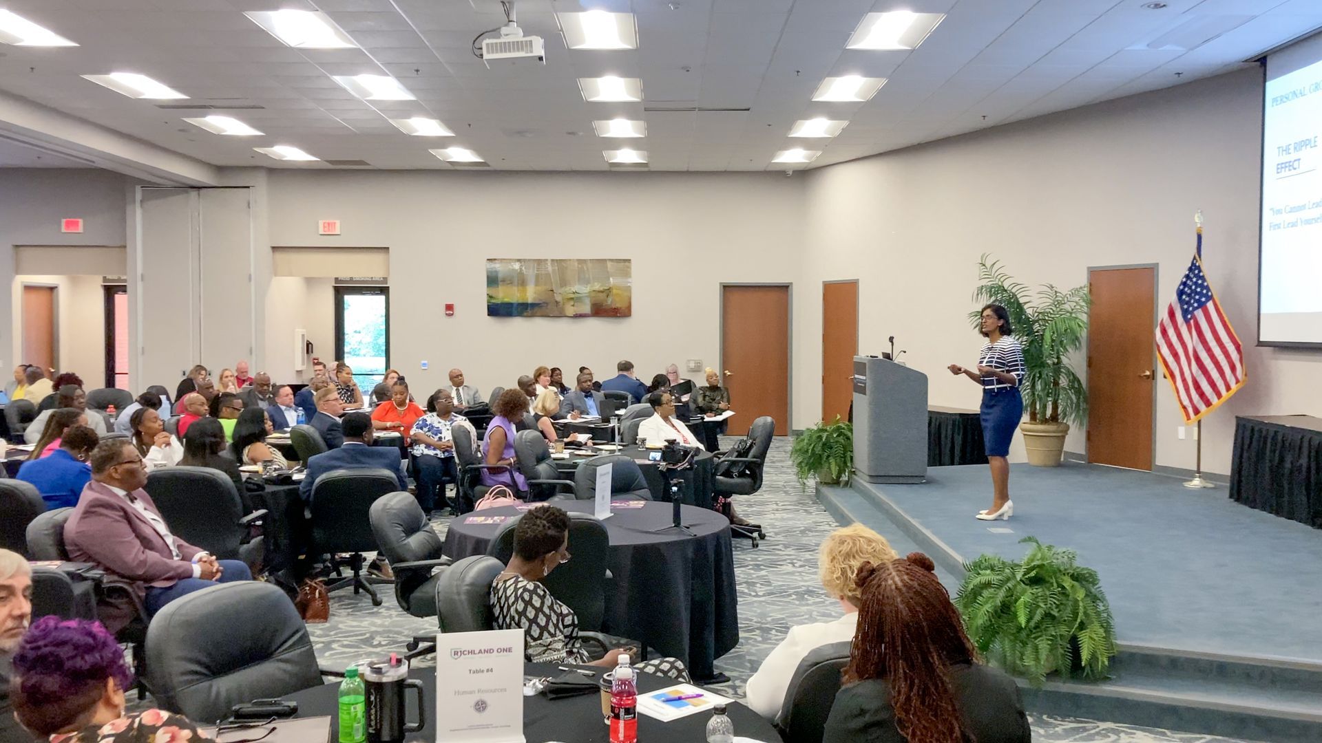 A woman is giving a presentation to a large group of people in a conference room.