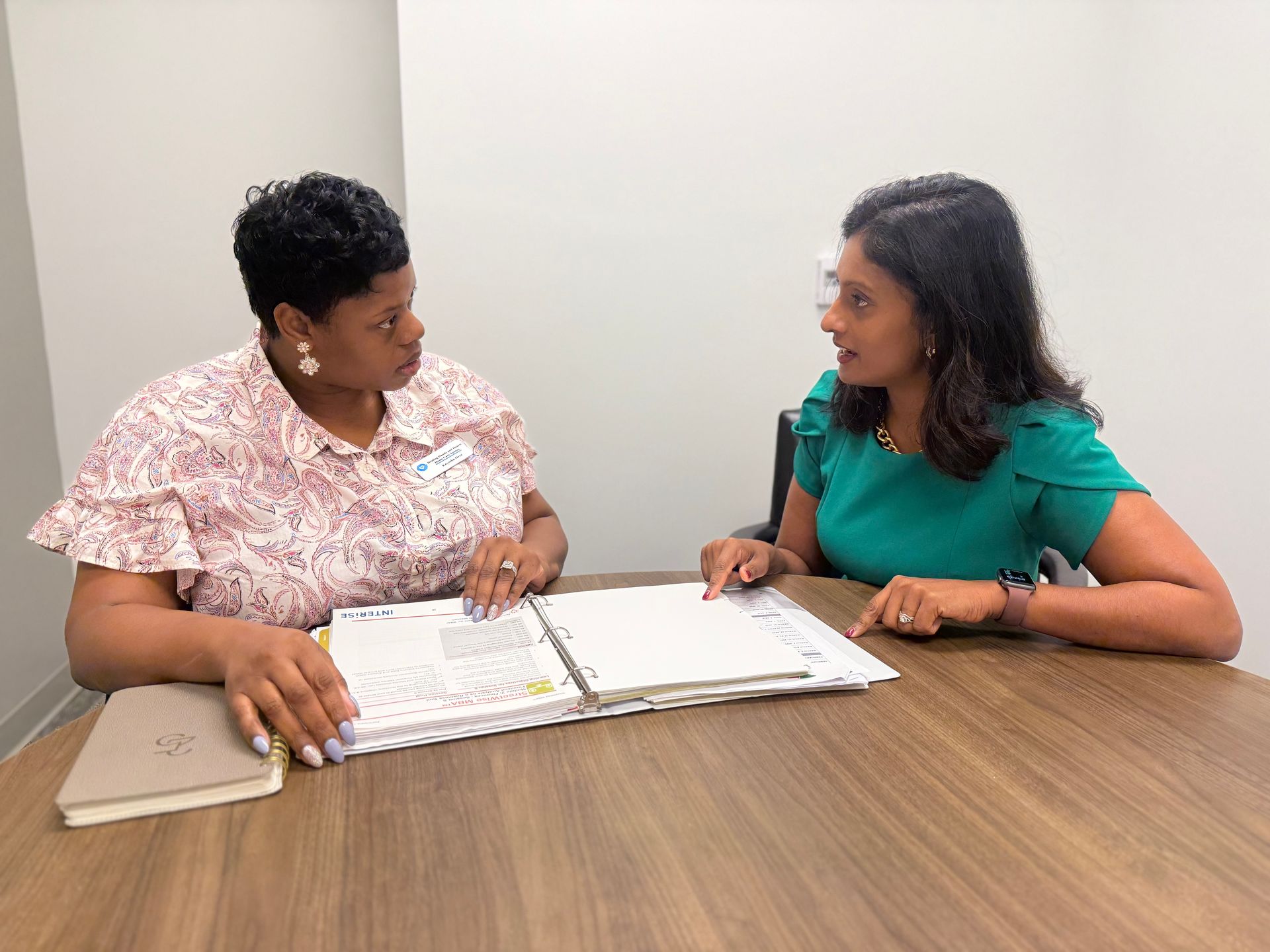 Two women are sitting at a table talking to each other.