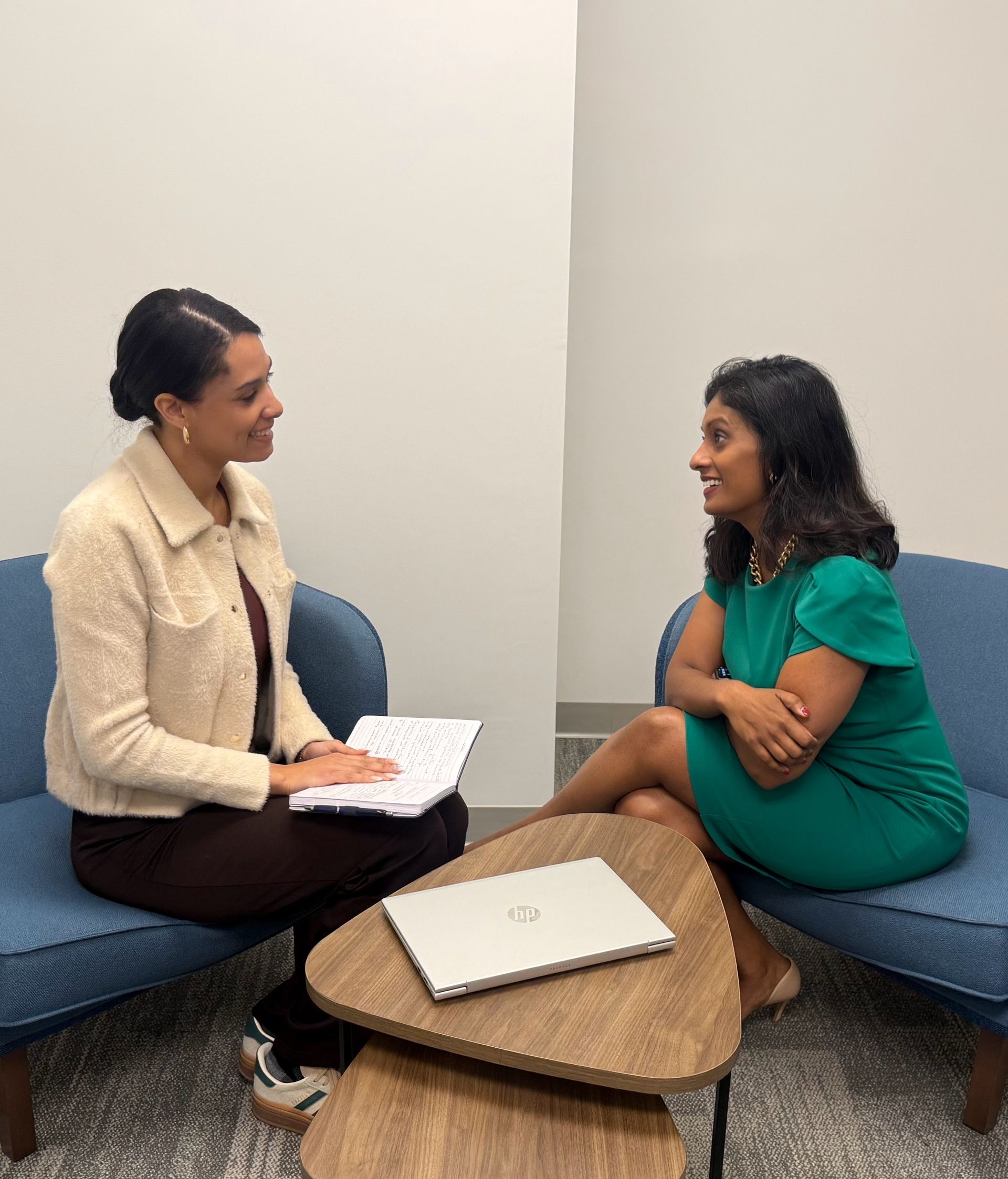Two women are sitting in chairs talking to each other.