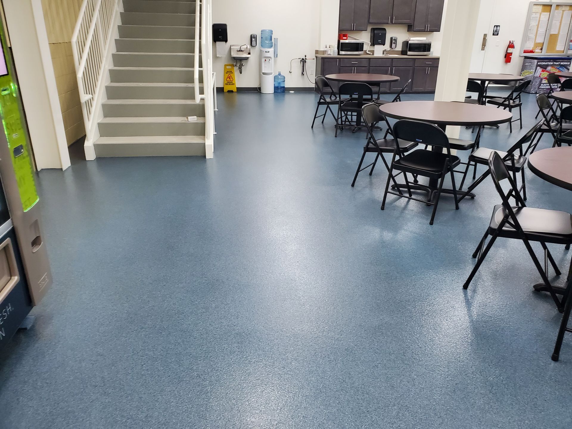 Blue car lifts in a shiny gray-floored automotive shop. Interior with white walls and windows.
