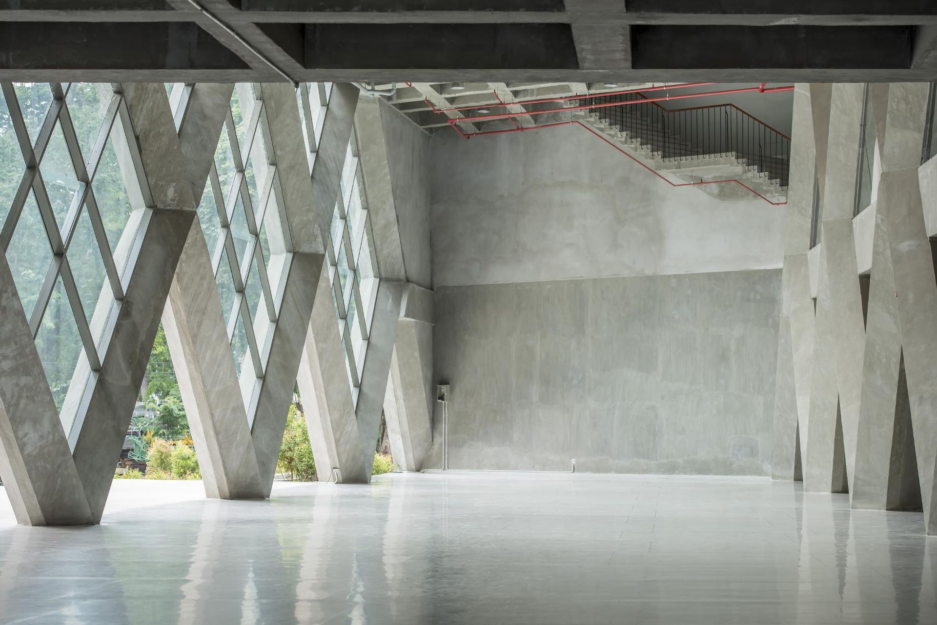 Modern concrete building interior with diamond-shaped window and reflective floor. 