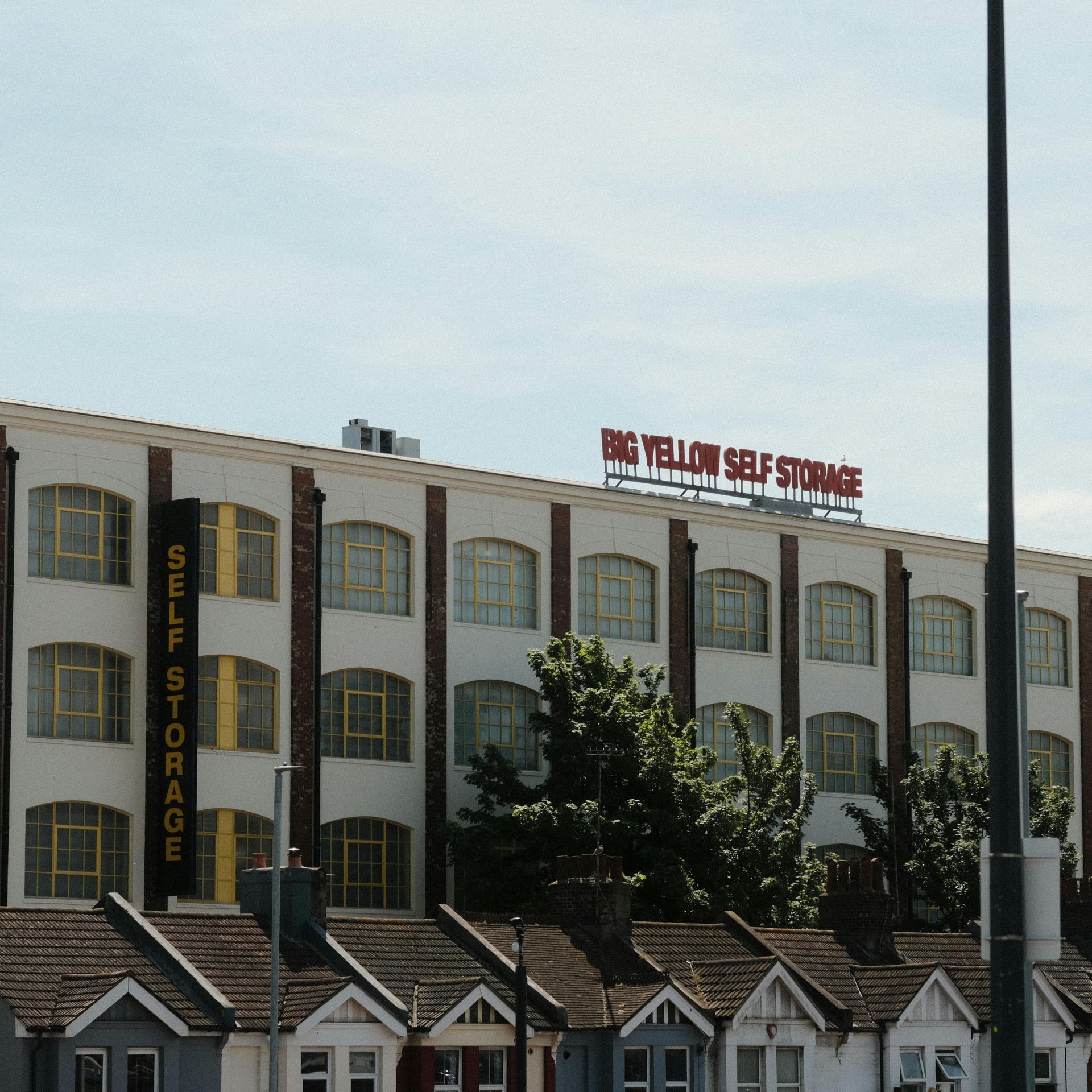 A large, multi-story Big Yellow Self Storage building behind a row of small residential houses.