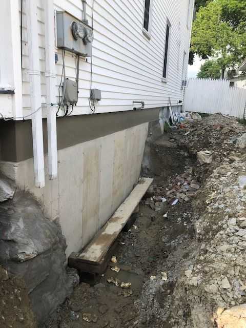 A white house is being remodeled with a concrete foundation