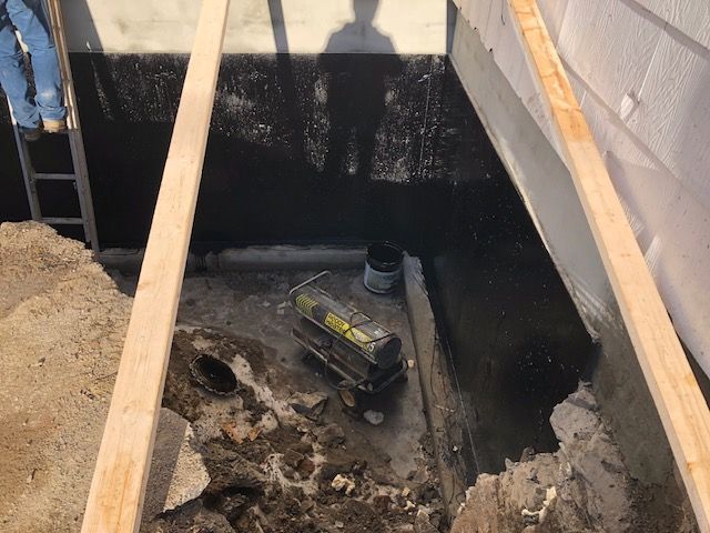 A person is standing in a hole in the ground next to a building.