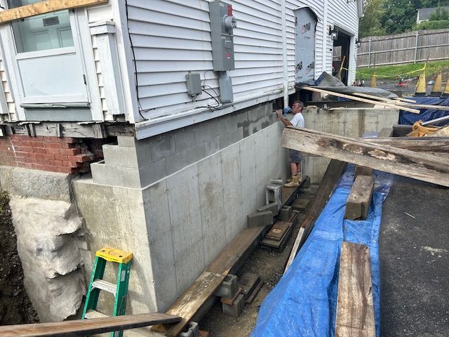 A man is standing in front of a house that is being remodeled.