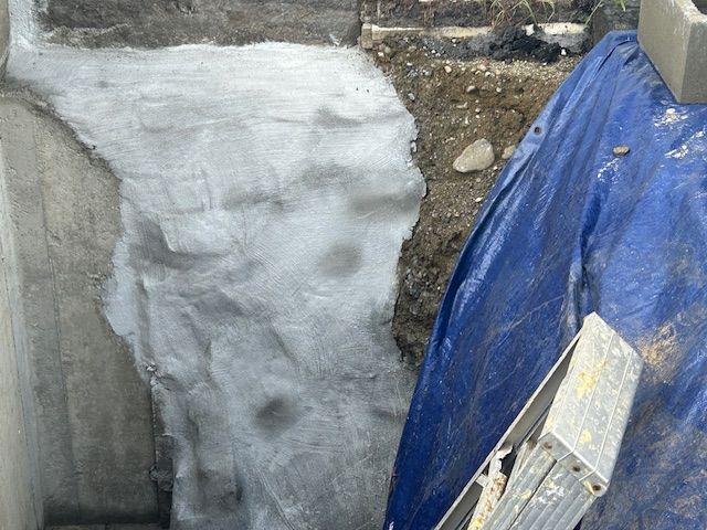 A blue tarp is covering a hole in the ground next to a ladder.