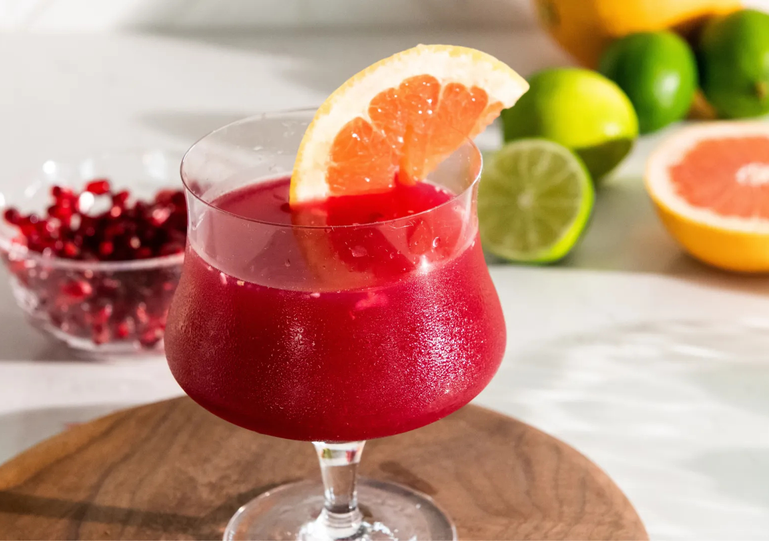 A glass of red liquid with a slice of grapefruit on top.