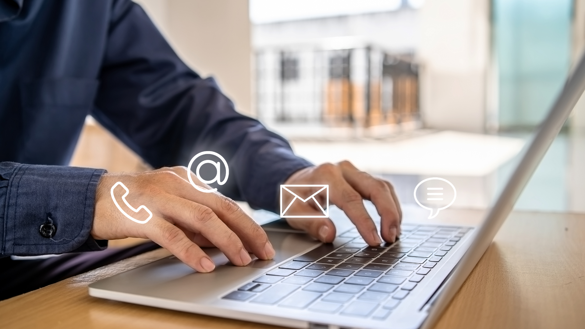 Person typing on laptop with contact icons: phone, email, and chat.