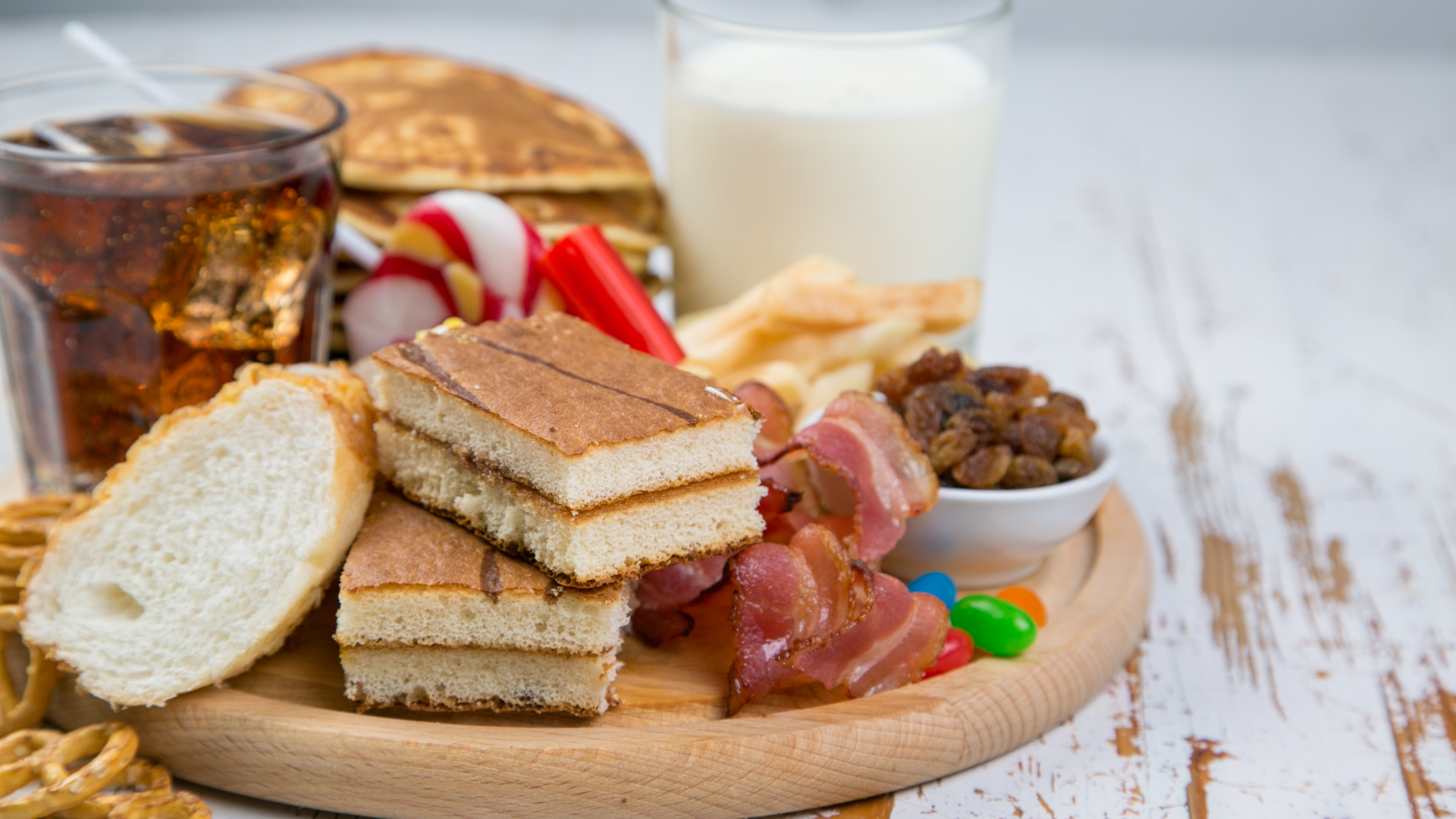 A wooden cutting board topped with a variety of snacks and drinks.