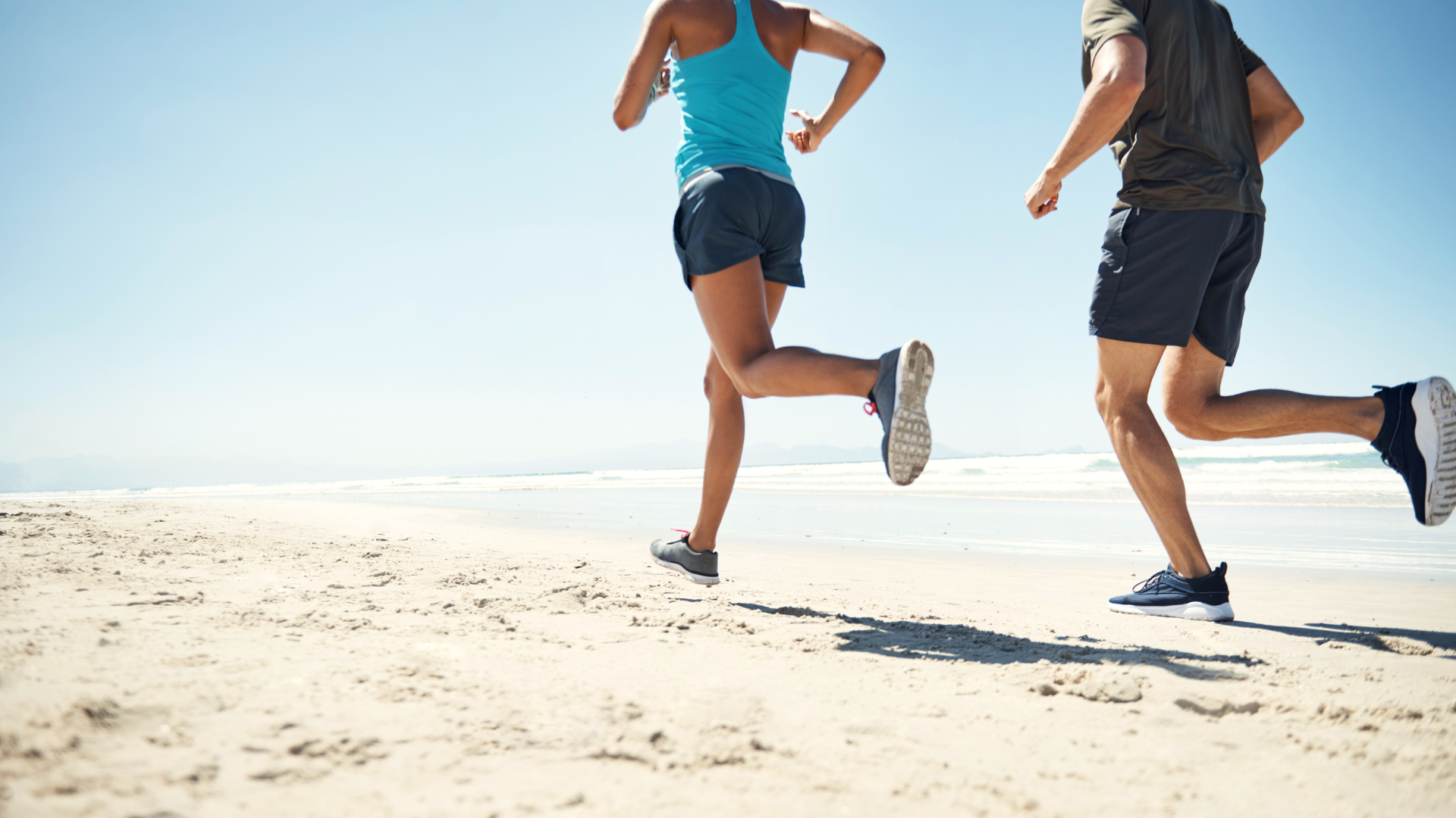 A man and a woman are running on the beach.