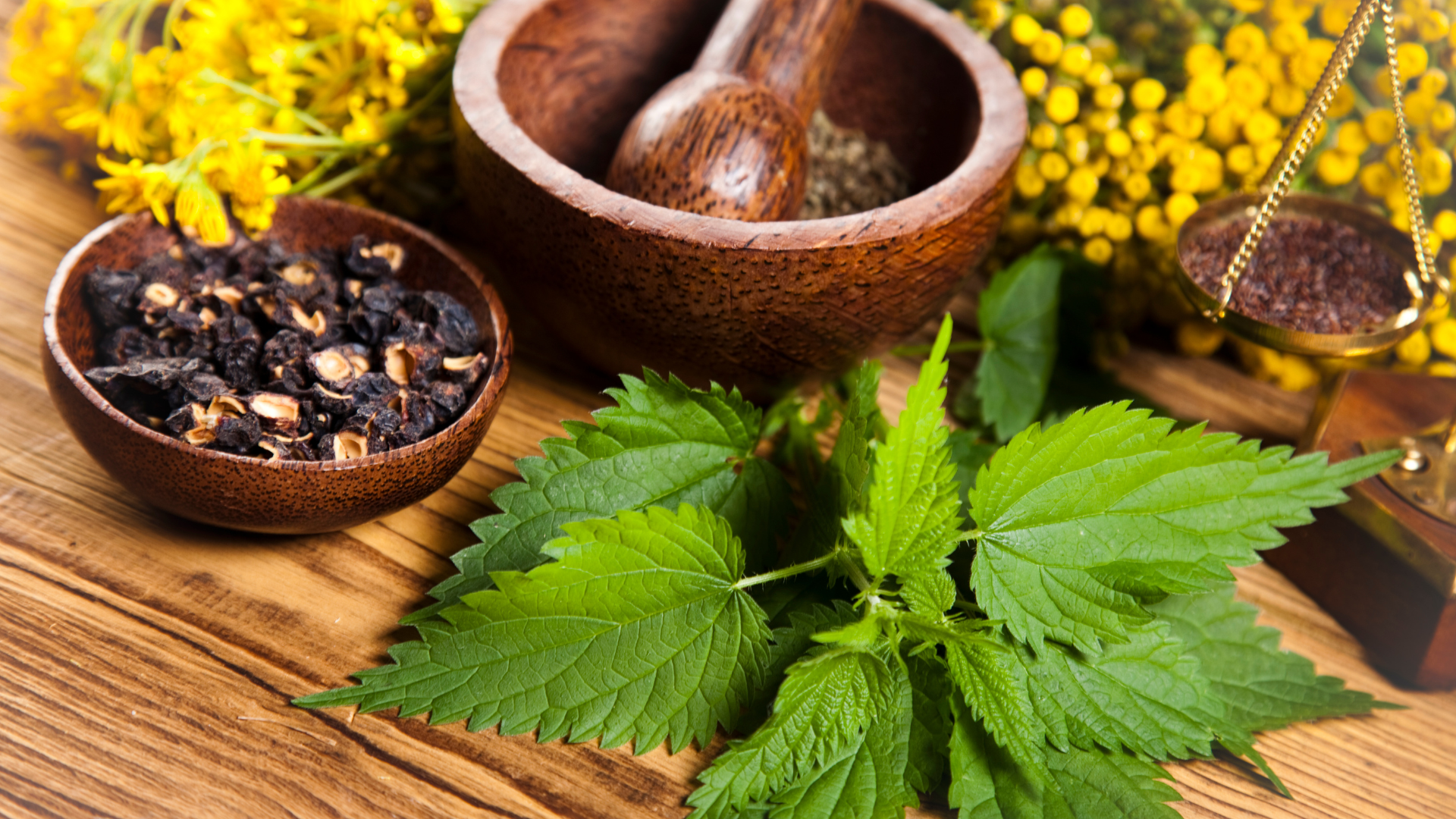 A wooden table topped with bowls of herbs and flowers.