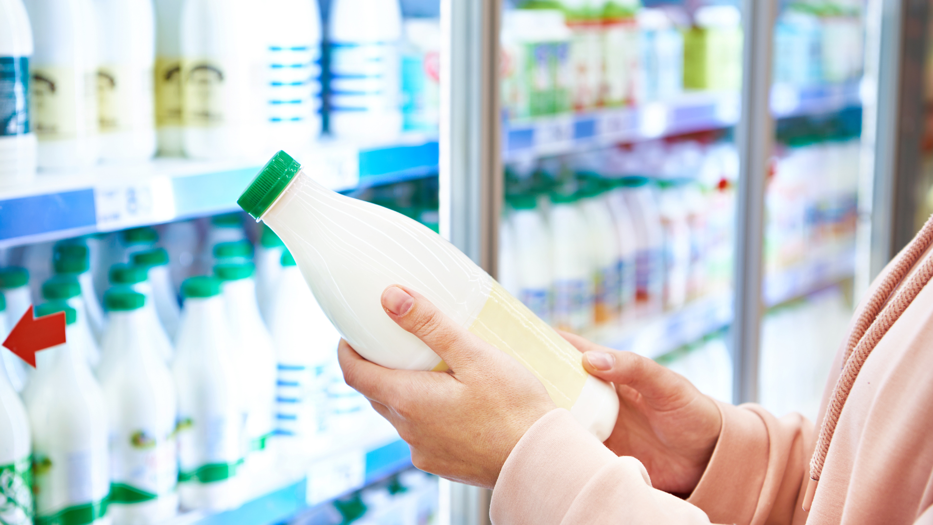 A woman is holding a bottle of milk in a grocery store.