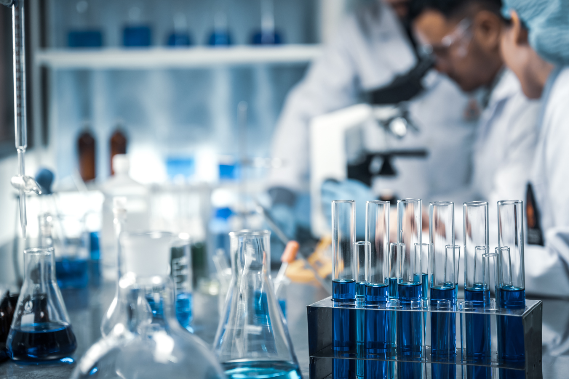 A group of scientists are working in a laboratory with a microscope and test tubes.