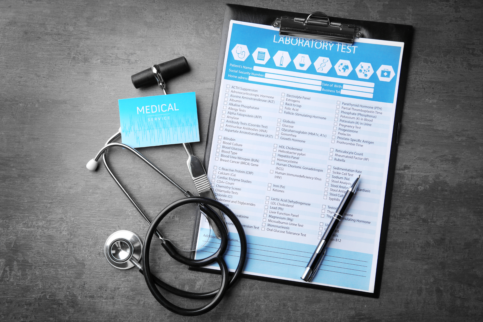 A stethoscope is sitting on top of a clipboard next to a pen.