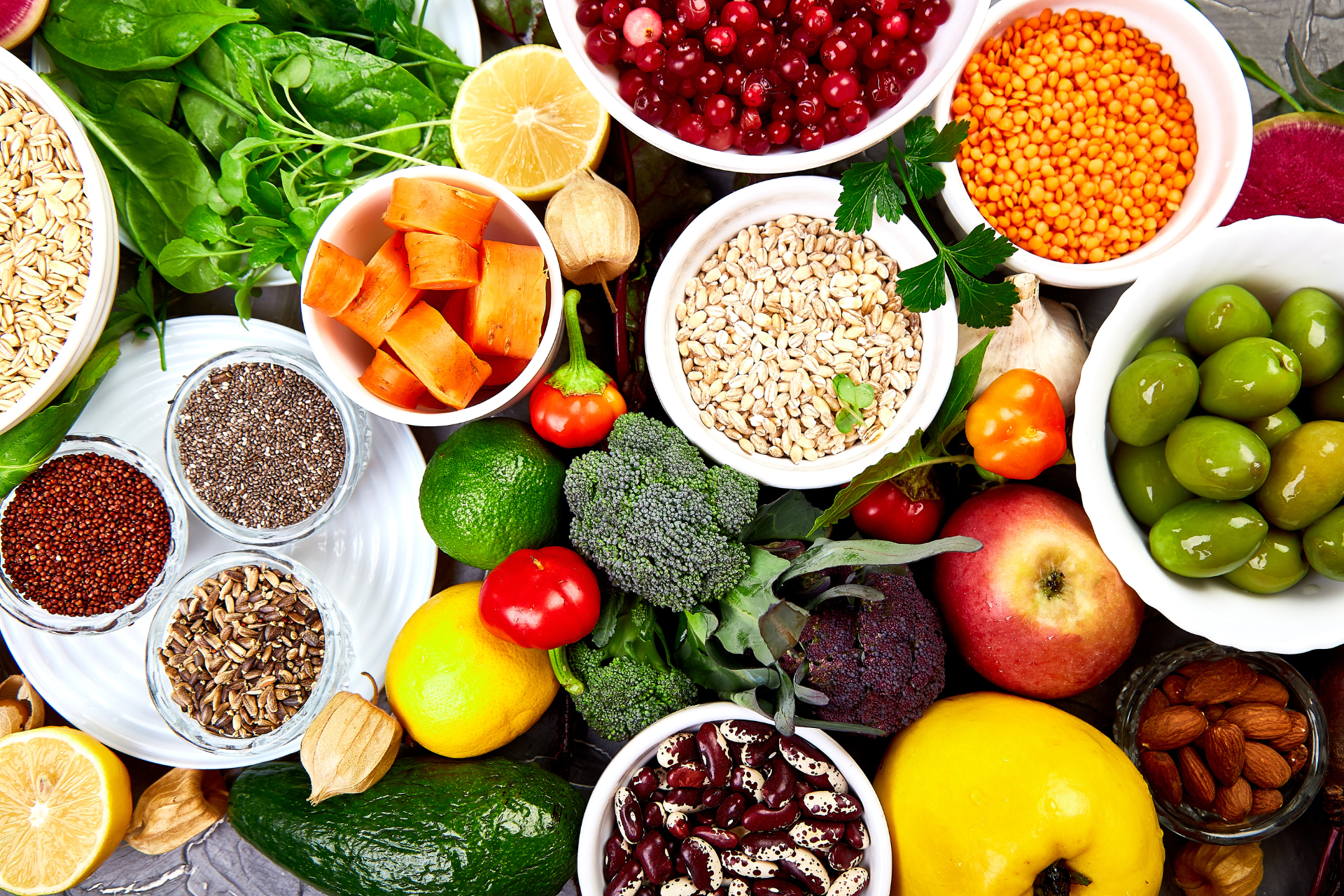 A variety of fruits and vegetables in bowls on a table.