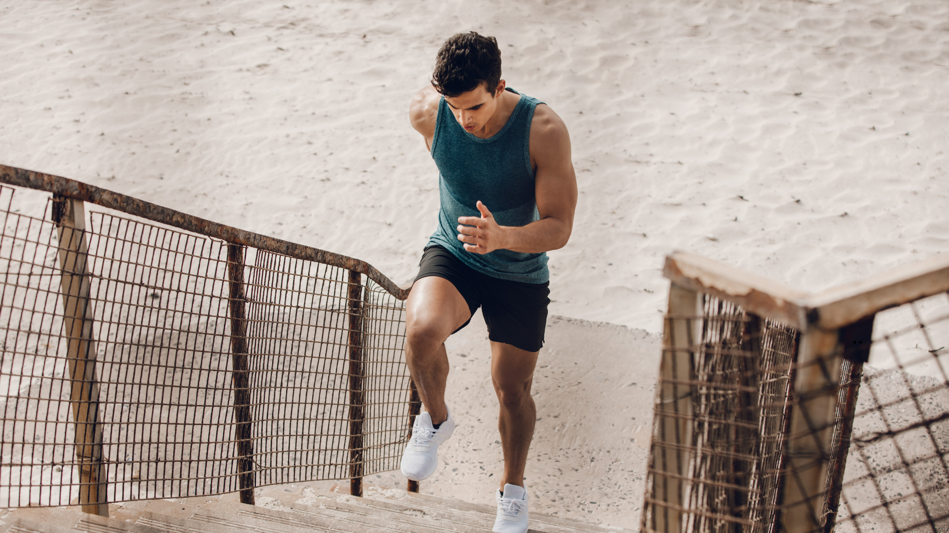 A man is running up stairs on a beach.