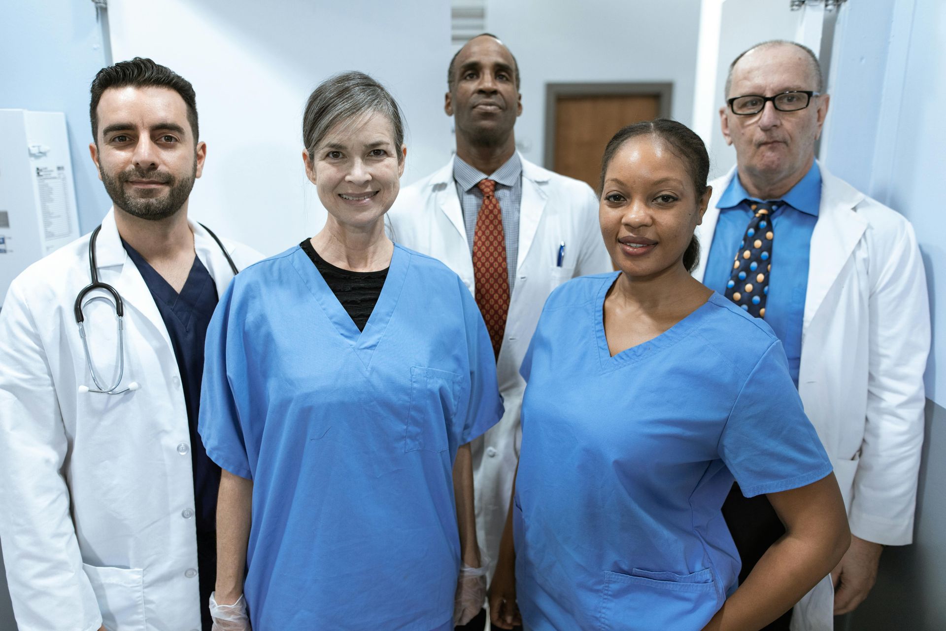 A group of doctors and nurses are posing for a picture in a hospital hallway.