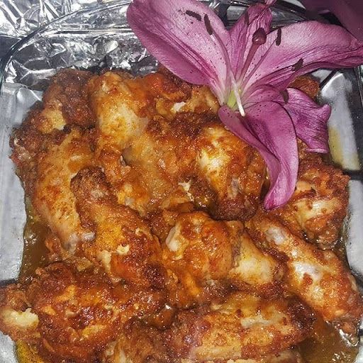 A close up of a plate of chicken wings with a purple flower on top.