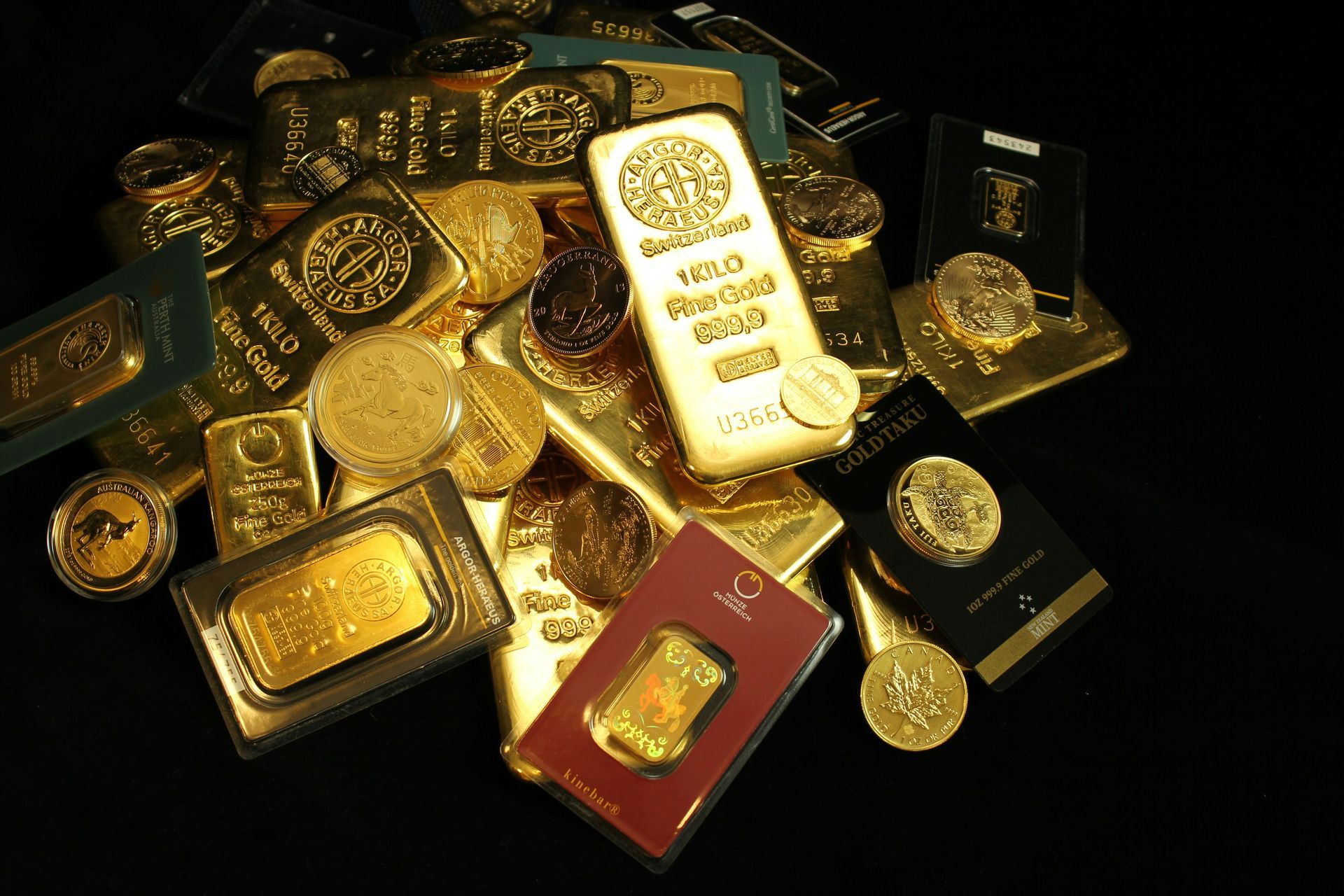 A pile of gold bars and coins on a black background