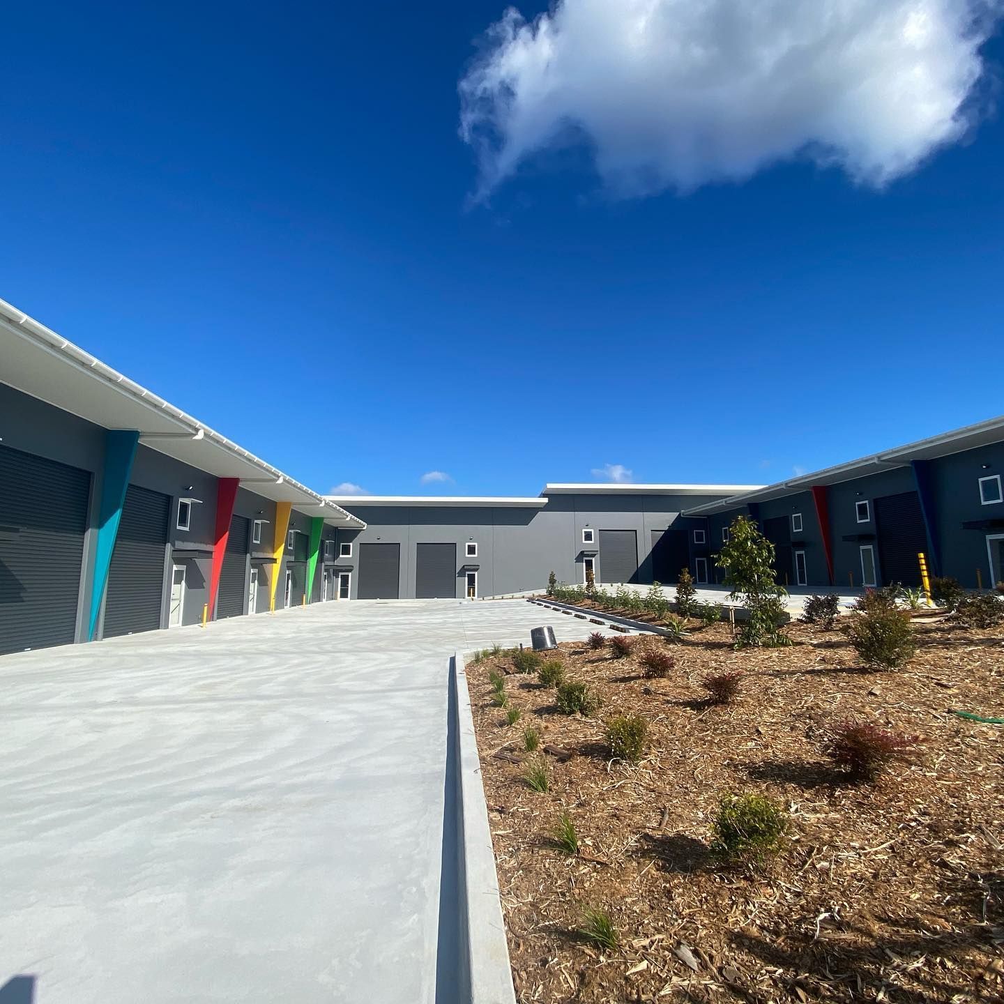 A row of buildings with a concrete driveway leading to them.
