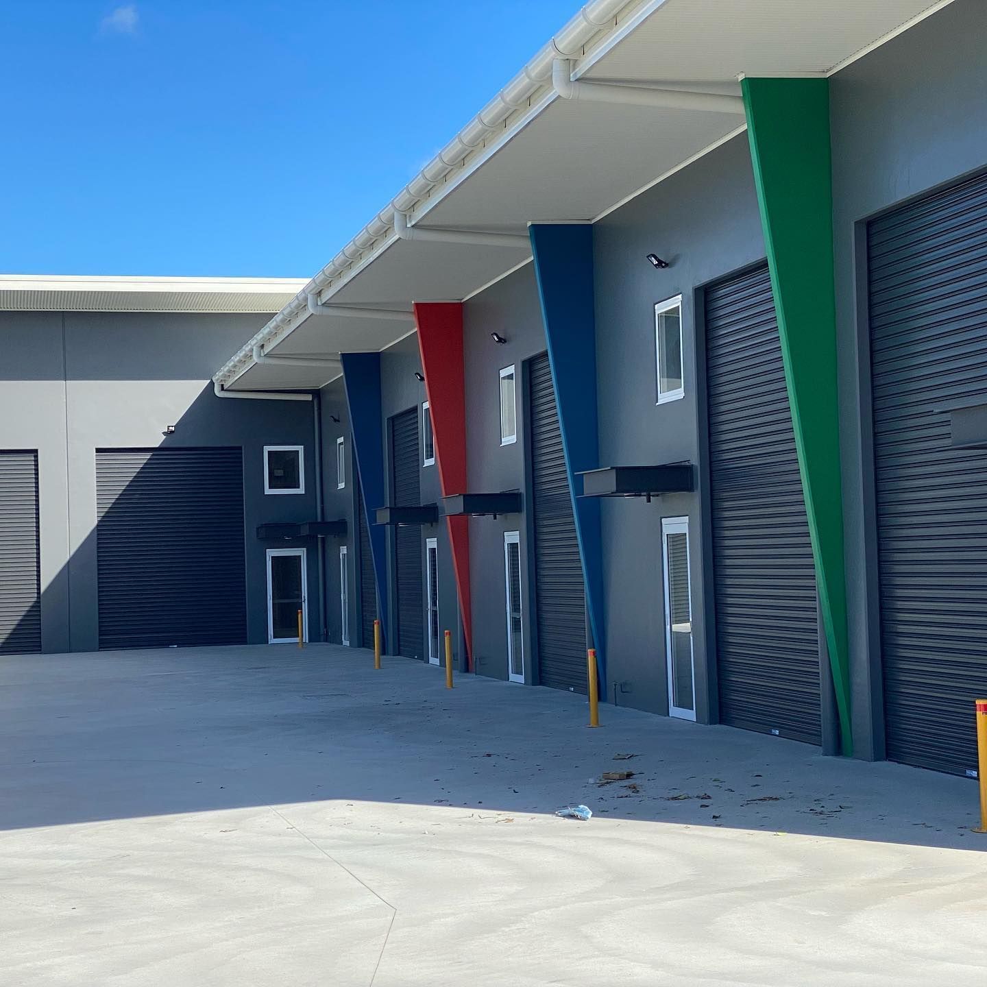 A row of buildings with red blue and green garage doors