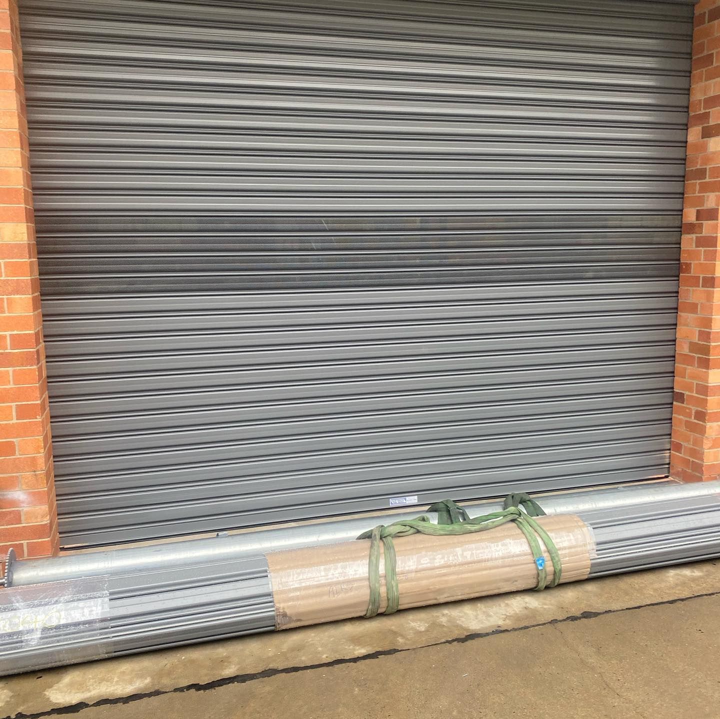 A roll up garage door is sitting in front of a brick building.