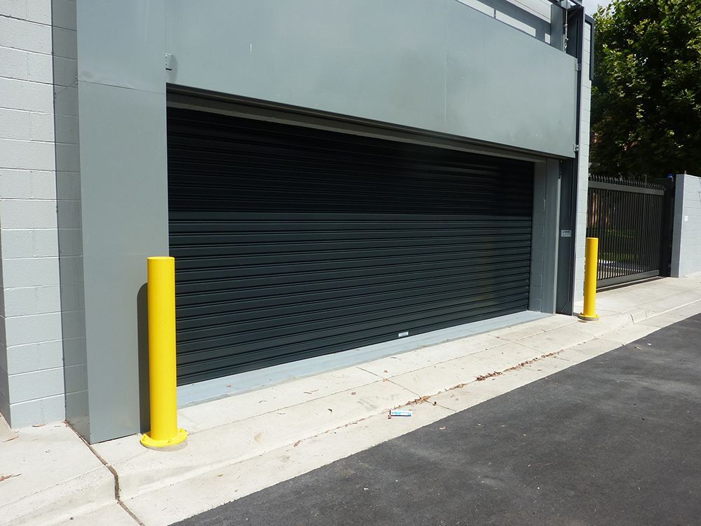 A garage door with a yellow pole in front of it