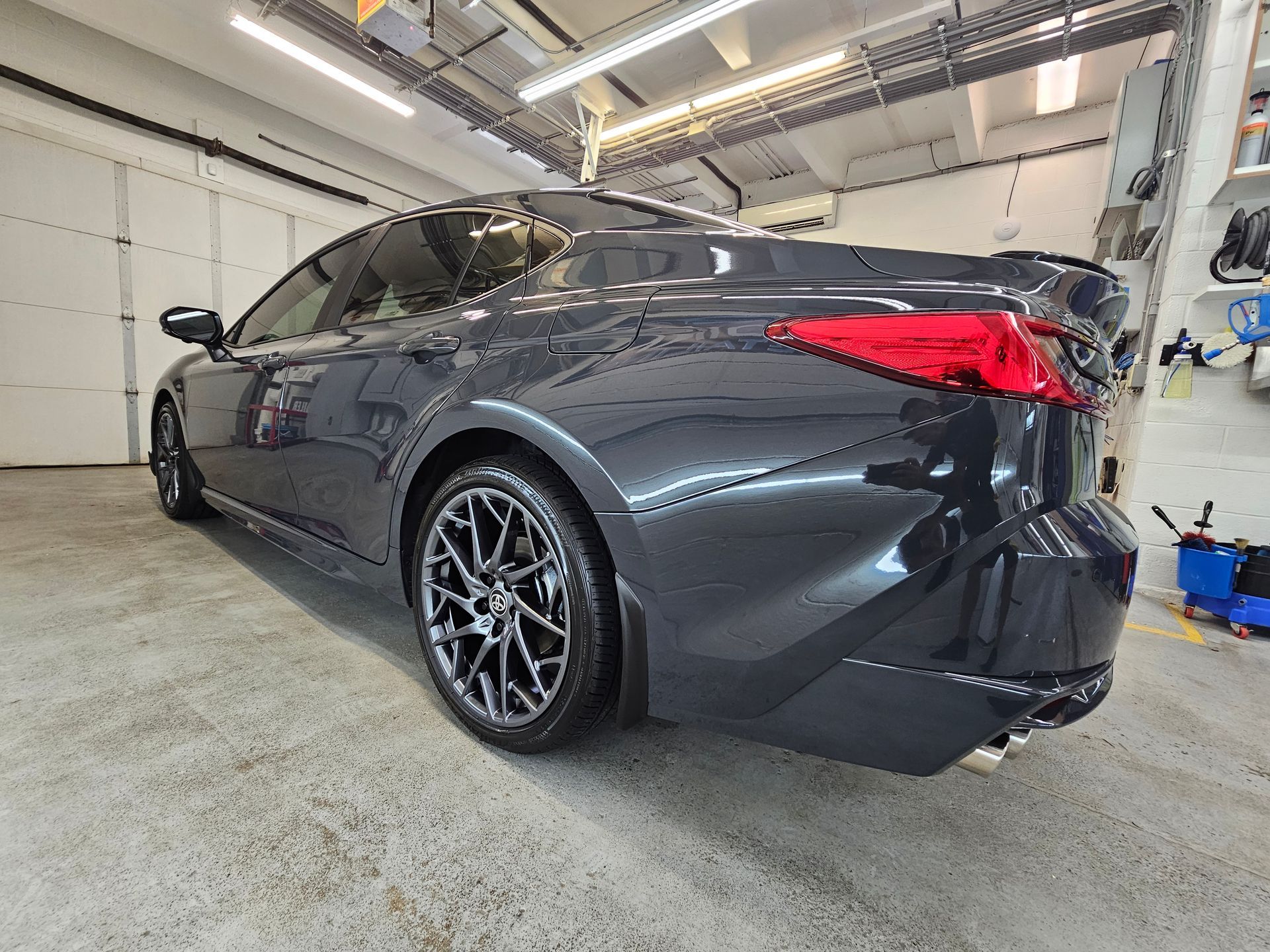 A black car is parked in a garage next to a garage door.