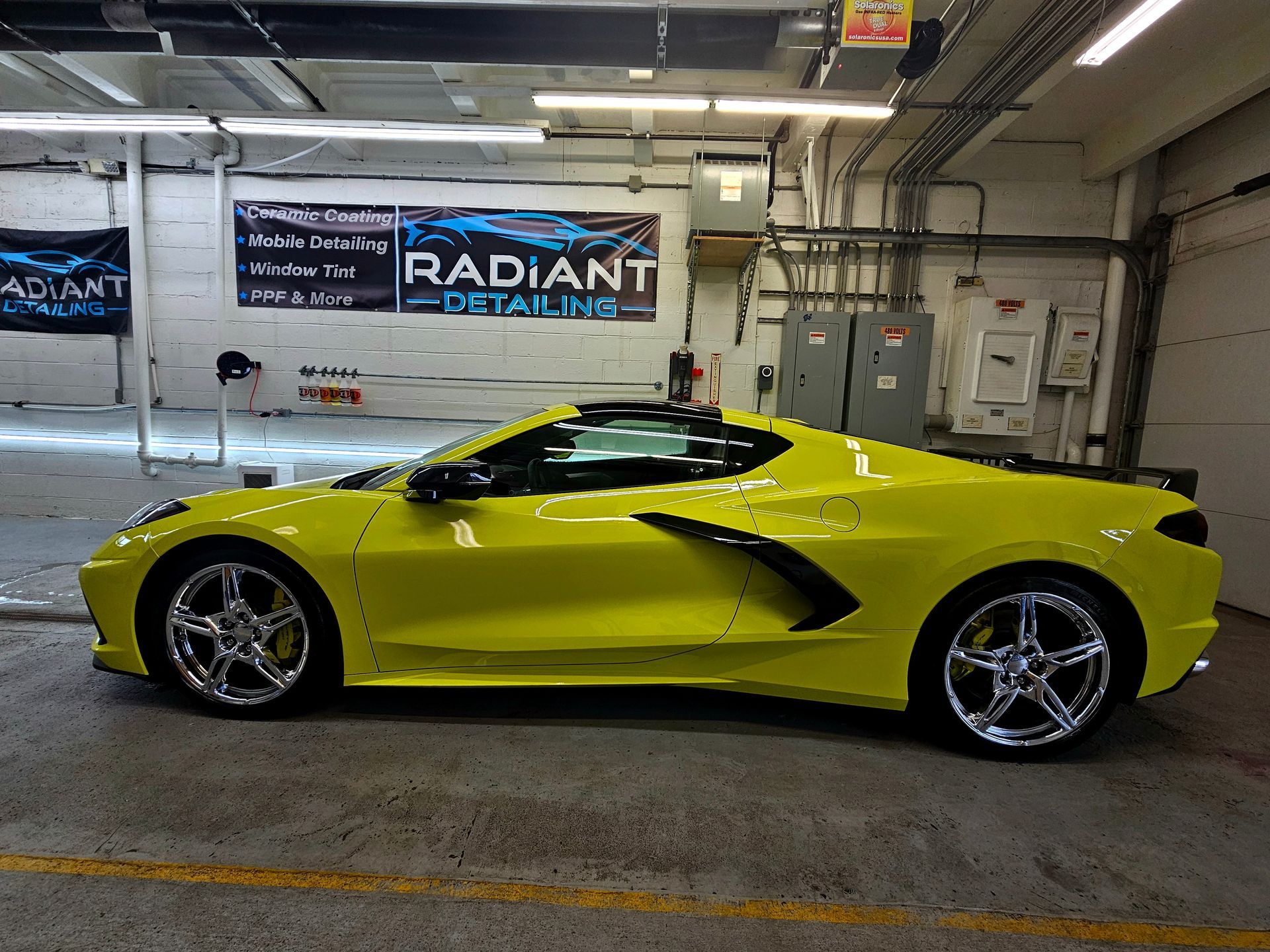 A yellow sports car is parked in a garage next to a sign that says radiant detailing