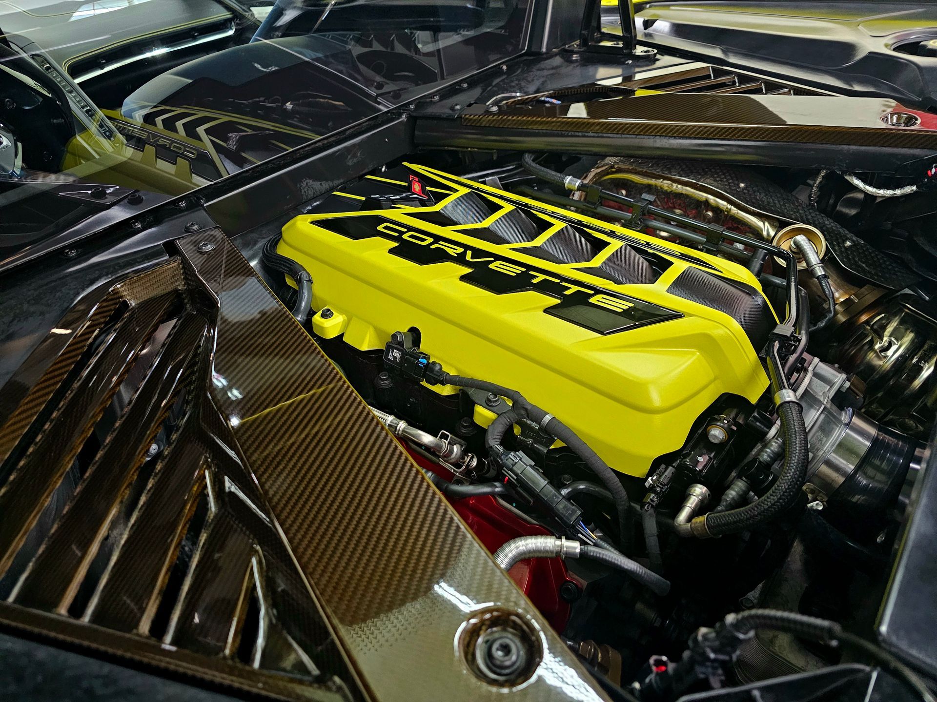 Yellow-covered Corvette engine in a black compartment, highlighting the powerful motor.