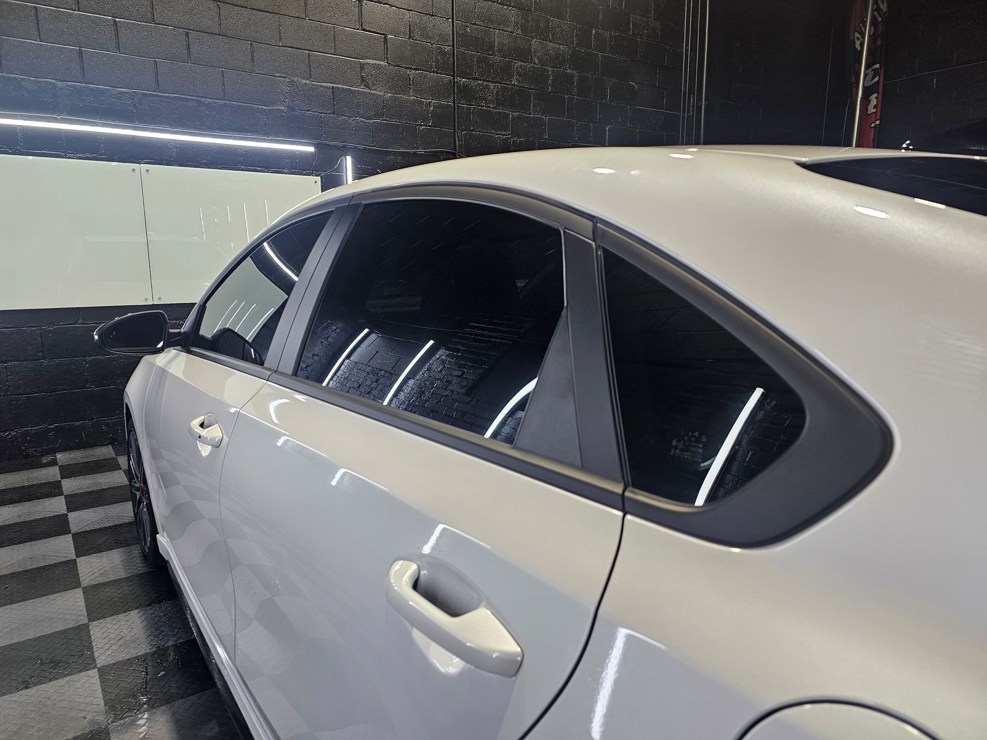 A white car with black windows is parked in a garage.