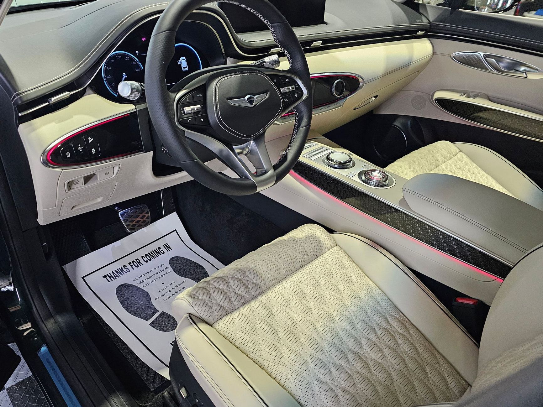 Interior view of a luxury car with a black steering wheel, white and beige seats, and a black dashboard.