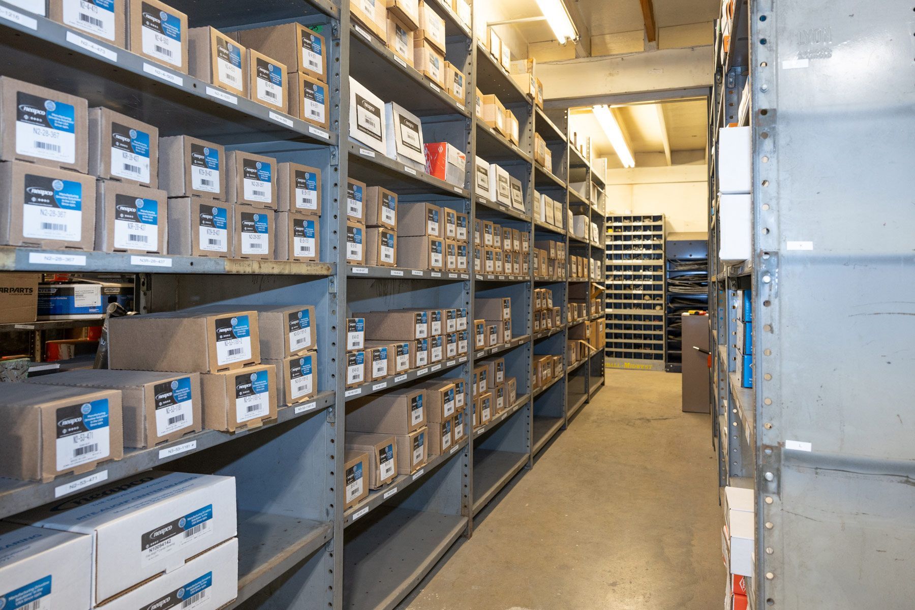 A mechanic working on machinery in a shop. He is holding a large, dark, circular part over a press.