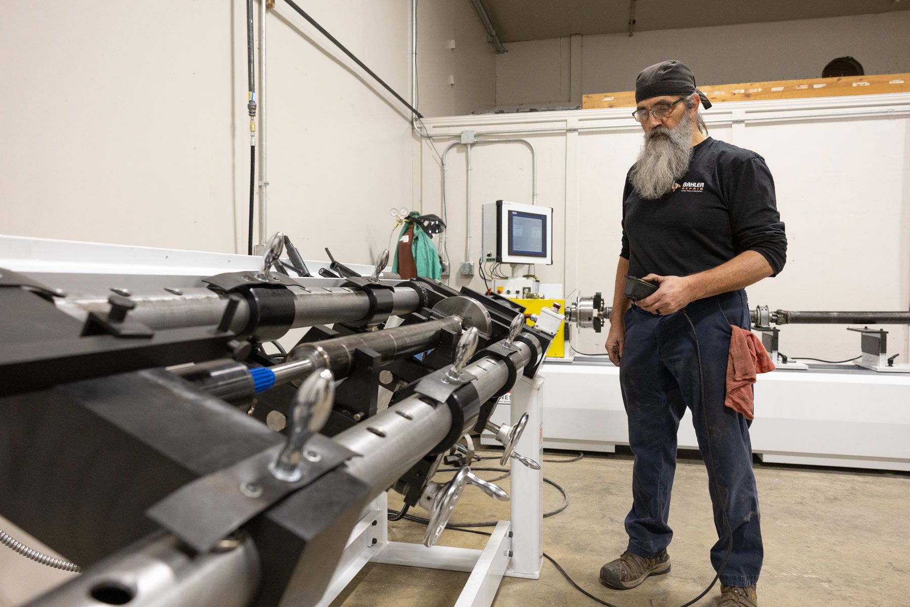 Man with beard in a workshop looking at driveshaft repair and balancing equipment