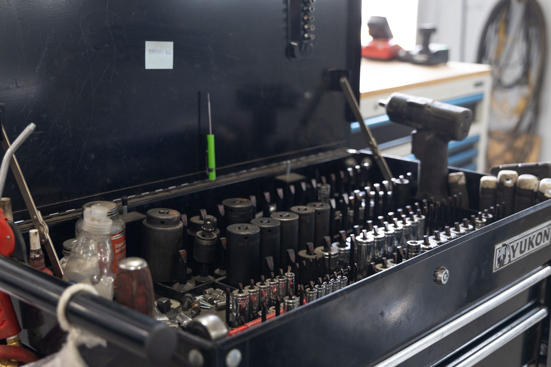 Open black tool chest filled with various tools.