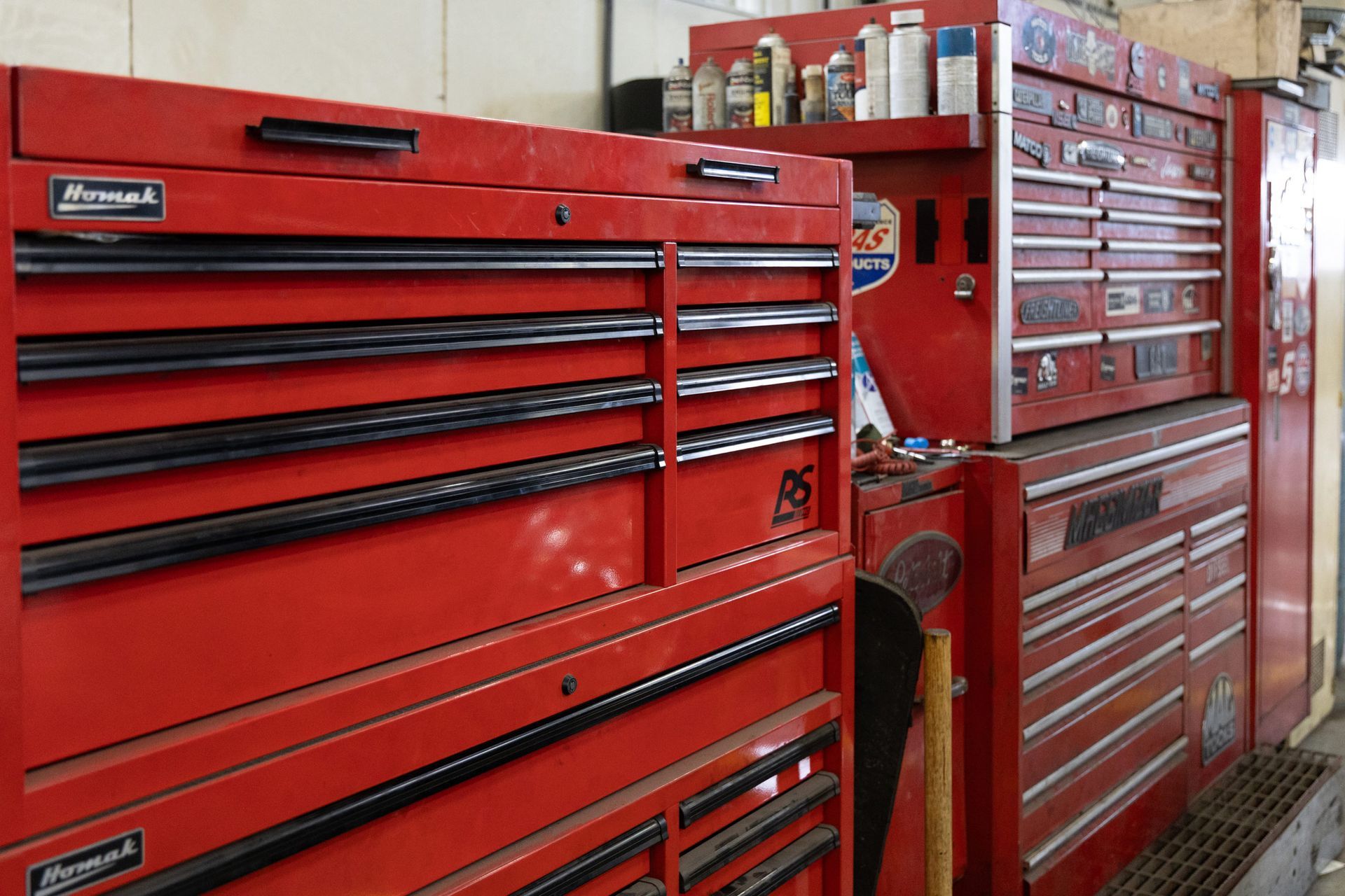 Several red tool chests of varying sizes, possibly in a garage or workshop. Some appear to be stacked, while others are side-by-side.