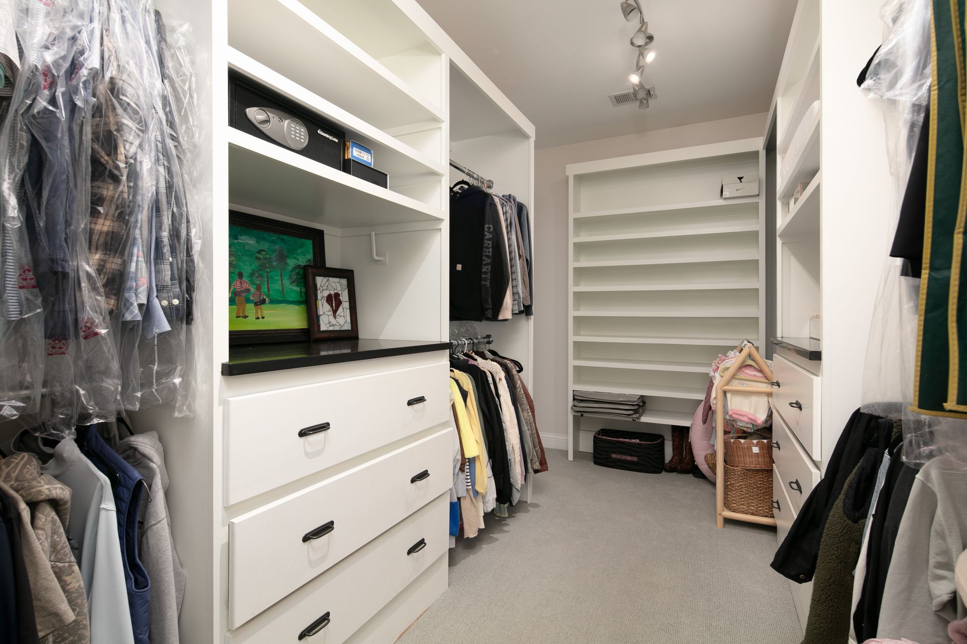 A white, organized walk-in closet featuring hanging garment racks, shelves, a chest of drawers, and a built-in shoe rack.