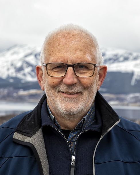 A man with glasses and a beard is wearing a blue jacket.