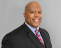 Richard Maddox II. A man in a suit and tie is smiling for the camera.