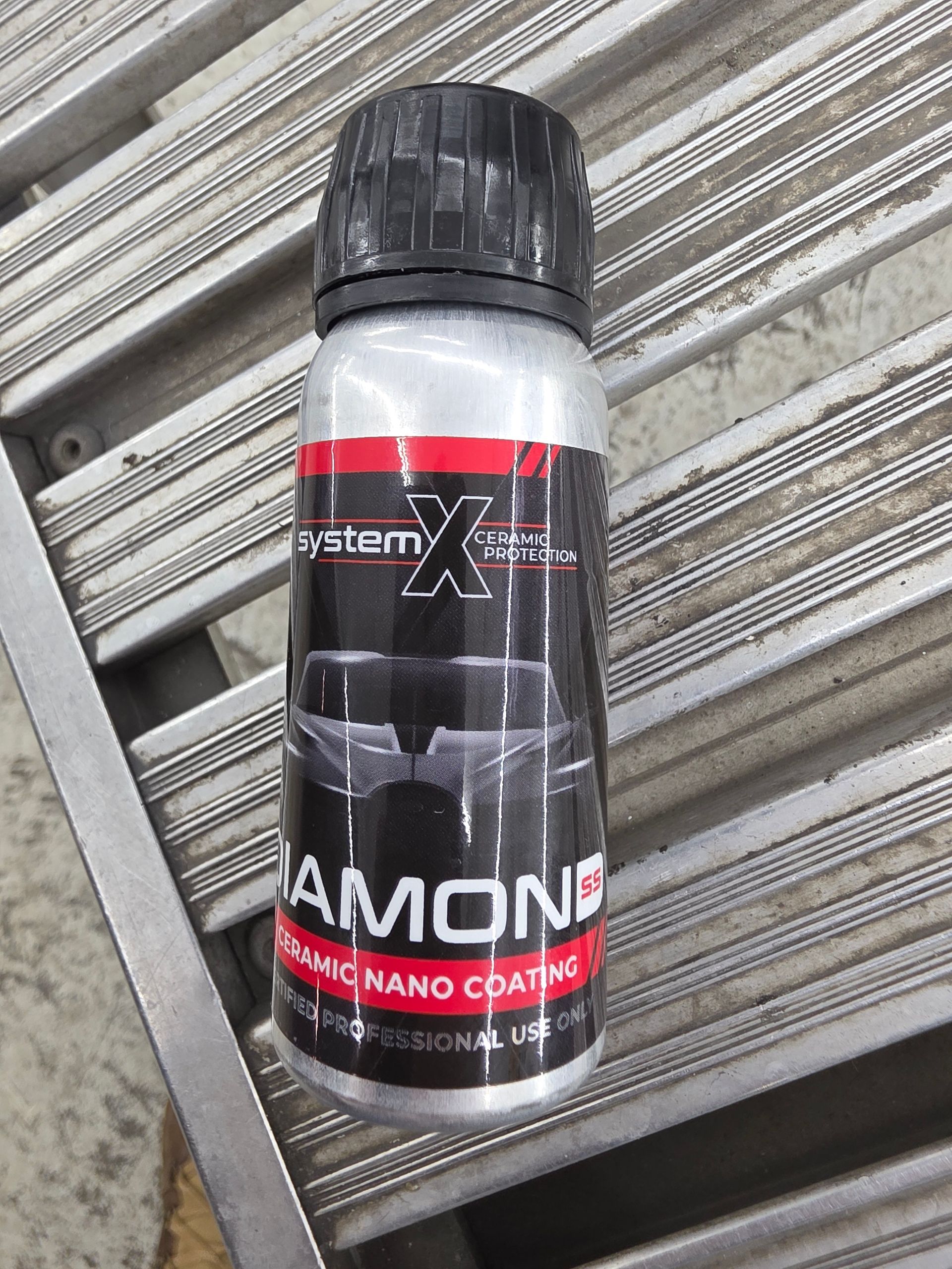 A person wearing black gloves applies a ceramic coating to a white car hood using a small blue applicator block.