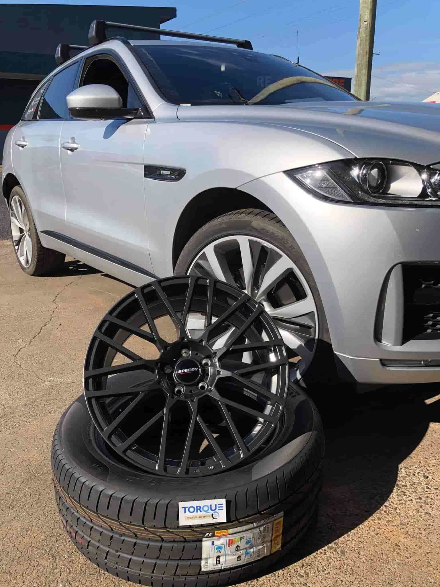 A Silver Car Beside a Stack of Tires and Wheels — Torque Tyres & Trailer Spares Cairns in Cairns, QLD