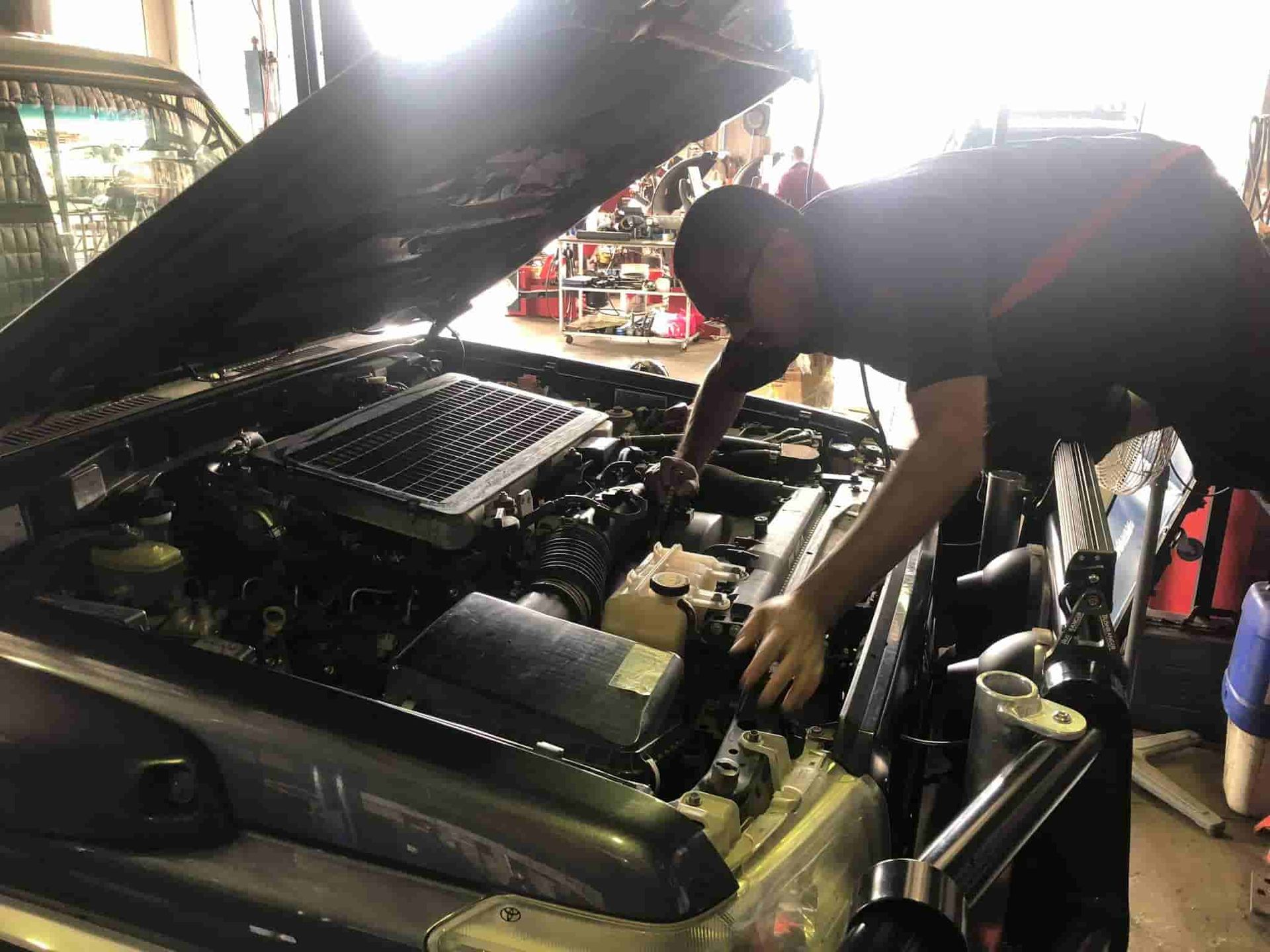 A Man Checking the Engine of A Car in A Garage — Torque Tyres & Trailer Spares Cairns in Cairns, QLD