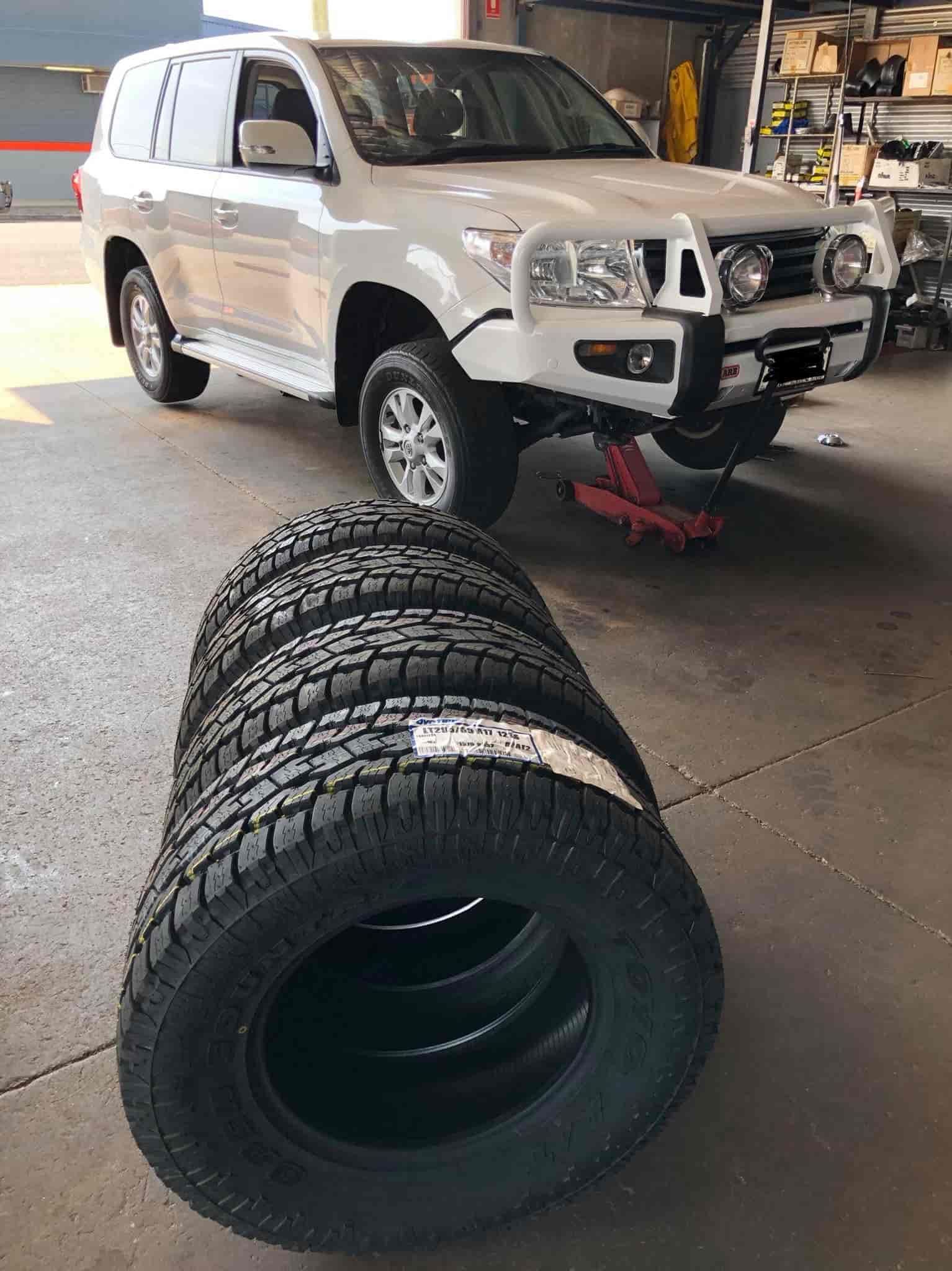 A White SUV Next to A Pile of Tires — Torque Tyres & Trailer Spares Cairns in Cairns, QLD